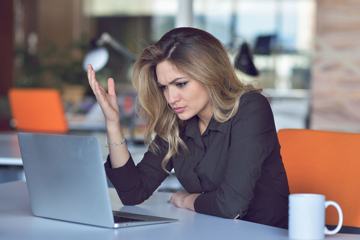 Mujer preocupada frente a su portátil por problemas de diseño web o marketing