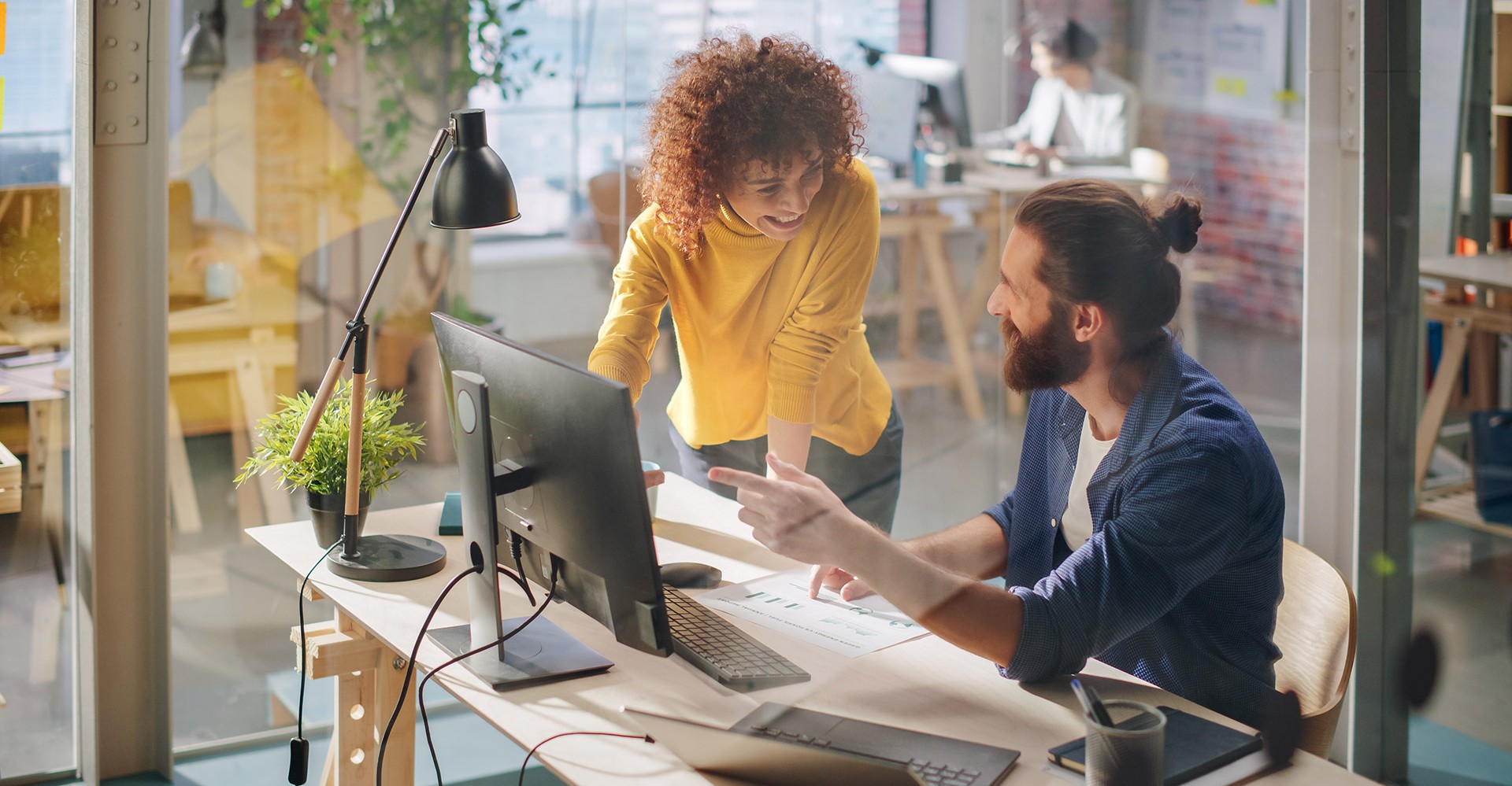 Zwei Angestellte aus einem Marketing-Team sitzen zusammen und diskutieren eine Strategie.