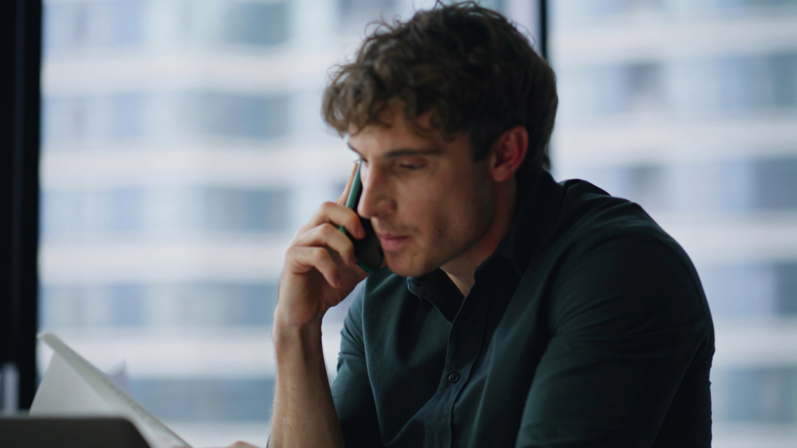 Asesor fiscal hablando por teléfono mientras revisa documentos sin una estrategia clara.